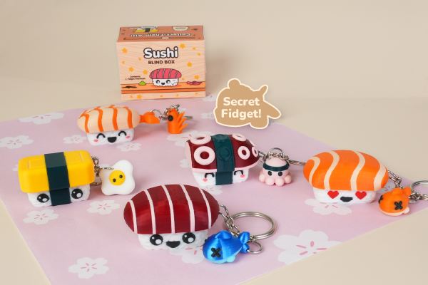 Collection of sushi-themed keychains on a pink mat with a Secret Fidget! label.